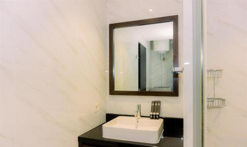 a bathroom with a white sink and a mirror at A Luxury 1BR Bali Style Apartment at Branz BSD City By Travelio in Tangerang