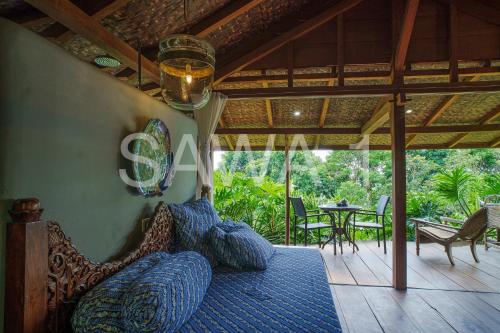 a bedroom with a bed on a porch with a table at Rumah Lereng Bandung in Bandung