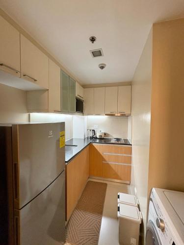 a kitchen with white cabinets and a stainless steel refrigerator at Modern Condo in Mactan Newtown - OPR Tower B in Lapu Lapu City