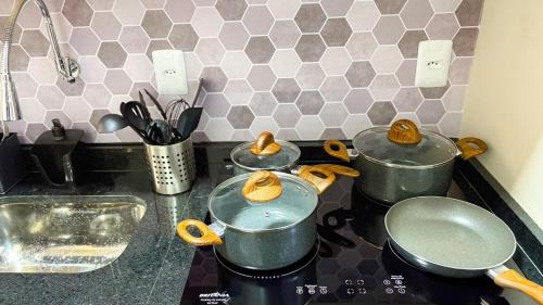 four pots and pans on a stove in a kitchen at Flat Santos Dumont in Rio de Janeiro