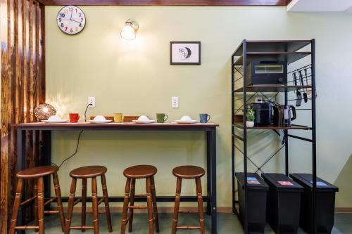 a bar with stools and a counter with a microwave at 鶴橋和モダン古民家 縁家 Enya-Japanese Townhouse 2min to Tsuruhashi Station Easy Access to Namba and Dotonbori in Osaka