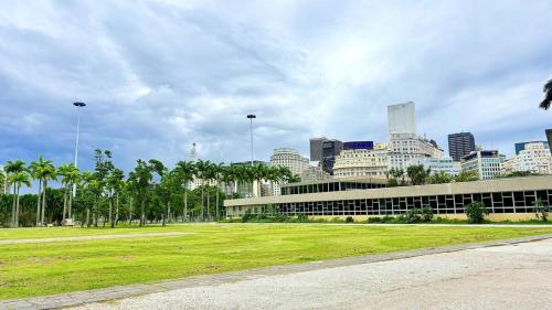 a building with a grass field in front of a city at Flat Santos Dumont in Rio de Janeiro