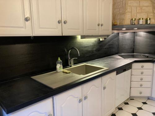 a kitchen with a sink and white cabinets at Ma demeure in Le Gué-de-Longroi