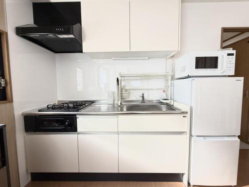 a white kitchen with a sink and a refrigerator at JR Soubusen Hirai 5mins walk Guest house! 2LDK,Max 8PP! Direct access to Kinshicyo,Akihabara,Shinjyuku! in Tokyo