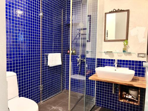a blue tiled bathroom with a sink and a shower at Hour Roots in Tainan