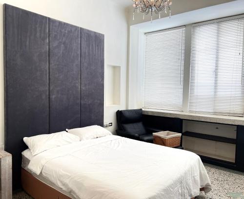 a bedroom with a large bed and a chair at Hour Roots in Tainan