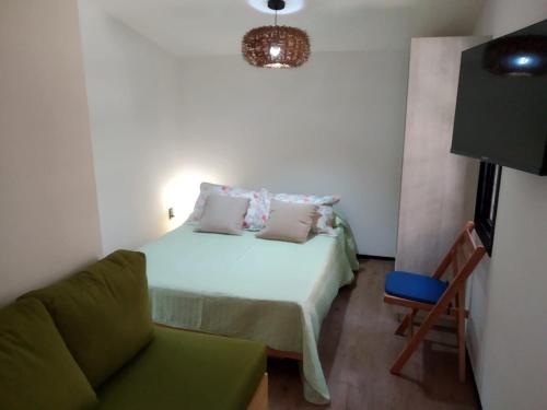 a small bedroom with a bed and a chair at Hermosa Cabaña tinny cálida y muy equipada in Santa Ana