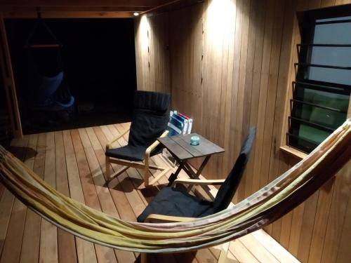 a hammock and a table and chairs in a room at Hermosa Cabaña tinny cálida y muy equipada in Santa Ana