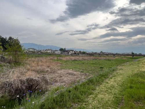 a field of grass with a bridge in the background at ぶどう畑に囲まれた貸切宿 バーベキュー可能 白百合醸造から徒歩すぐ"Vineyard Vista" Vacation rental BBQ permitted short walk from Winery in Yamanashi