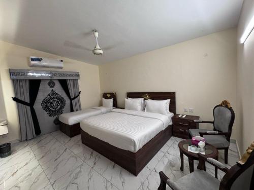 a hotel room with two beds and a chair at A One Boutique Hotel Dha in Karachi