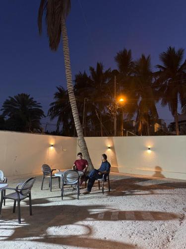 two men sitting at a table under a palm tree at A One Boutique Hotel Dha in Karachi