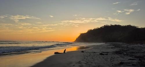 a beach with the sun setting on the water at Bus hotel Playa Barrigona, entre Sàmara y Nosara in Nicoya