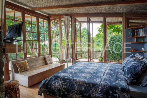 a bedroom with a bed and a bench and windows at Rumah Lereng Bandung in Bandung