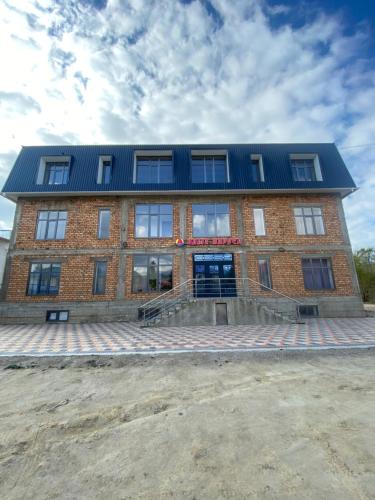 a large brick building with a blue roof at Алые Паруса in Cholpon-Ata