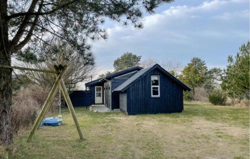 a blue house in a field with a swing at Awesome Home In Millinge With Sauna in Millinge