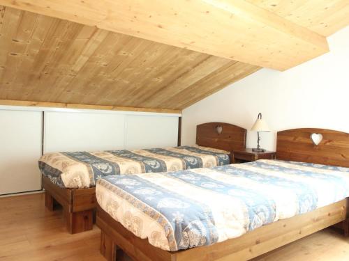 two beds in a room with wooden ceilings at Duplex 3 chambres pour 8 pers avec jolie vue village à Aussois - FR-1-508B-16 in Aussois