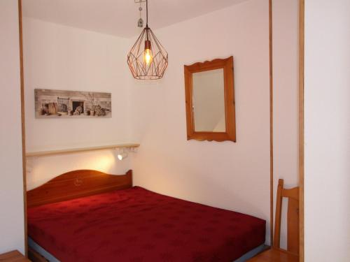 - une petite chambre avec un lit rouge et un miroir dans l'établissement Appartement cosy avec terrasse et parking sous-terrain à Aussois - FR-1-508B-27, à Aussois