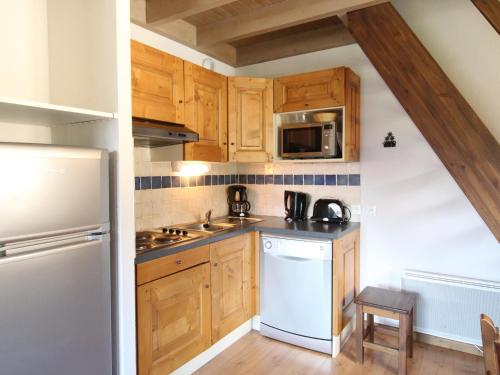 une cuisine avec des armoires en bois et un réfrigérateur blanc dans l'établissement Appartement spacieux à Aussois pour 6 personnes - FR-1-508B-28, à Aussois
