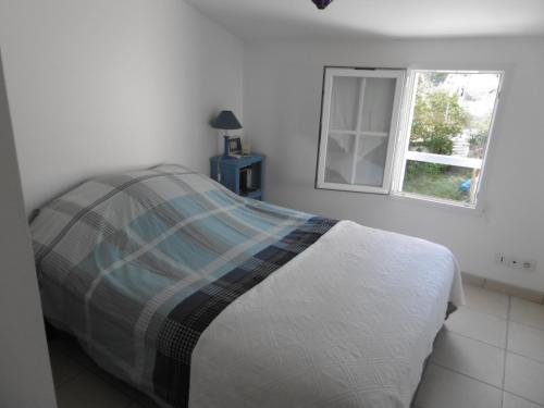 un lit dans une chambre blanche avec une fenêtre dans l'établissement Maison confortable à Barbâtre pour 4 personnes, proche plage - FR-1-823-150, à Barbâtre