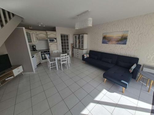 un salon avec un canapé bleu et une cuisine dans l'établissement Duplex T3 lumineux avec garage à Berck-Plage - FR-1-674-50, à Berck-sur-Mer