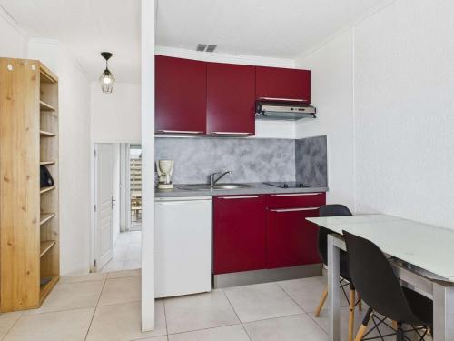 une cuisine avec des placards rouges et une table avec des chaises dans l'établissement Appartement T2 en front de mer au Grau d'Agde pour 4 personnes - FR-1-423-324, au Grau-dʼAgde
