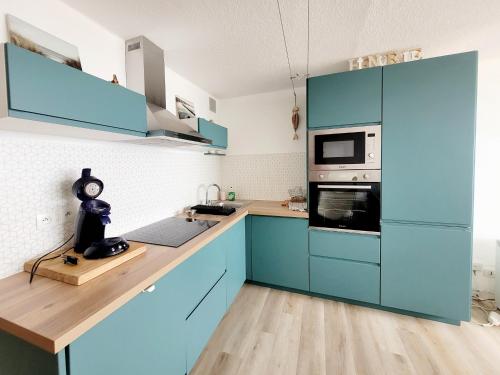 une cuisine avec des armoires bleues et un comptoir dans l'établissement T2 à Canet-en-Roussillon - 4 personnes, parking, vue mer - FR-1-794-162, à Canet