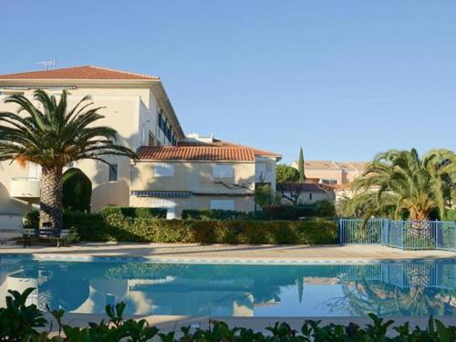 une maison avec un palmier et une piscine dans l'établissement Appartement T2 avec terrasse, piscine et parking, proche plage - FR-1-803-93, au Lavandou