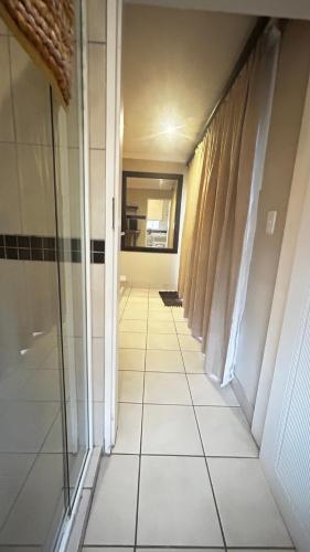 a hallway with a tile floor and a mirror at Artzys Studio in Northriding