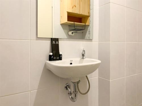baño con lavabo blanco y armario en Minimalist Studio Room at Tokyo Riverside PIK 2 Apartment By Travelio, en Rawalembang