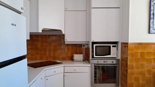 une cuisine avec des armoires blanches et un micro-ondes dans l'établissement Le CALIFORNIA T3, à Antibes