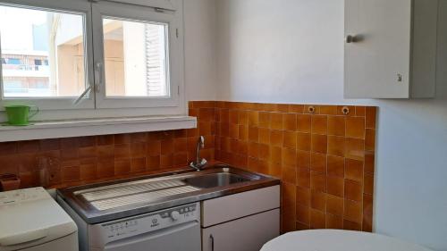 une petite cuisine avec un évier et une fenêtre dans l'établissement Le CALIFORNIA T3, à Antibes