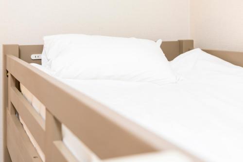 two beds in a bedroom with white sheets at Otani gofuku in Fukuoka