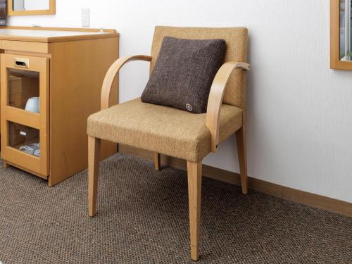 a chair with a pillow on it next to a cabinet at Nishitetsu Inn Tenjin in Fukuoka