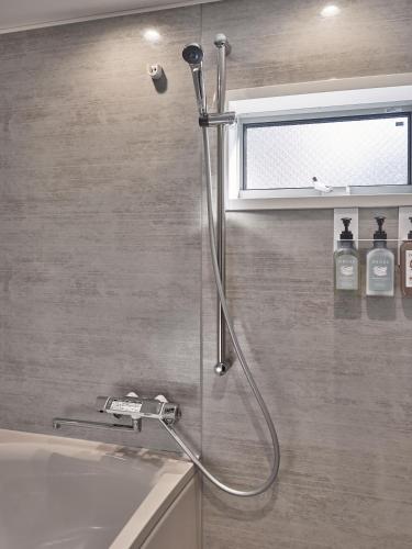 a shower in a bathroom next to a sink at LUXU Urban Shinjuku - 4min to Shinjuku, 10min to Shibuya in Tokyo