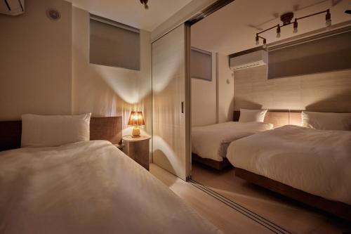 a hotel room with two beds and a mirror at LUXU Urban Shinjuku - 4min to Shinjuku, 10min to Shibuya in Tokyo