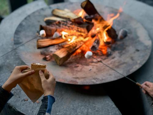 a person holding a piece of food in front of a fire at Glamprook Iizuna in Iizuna