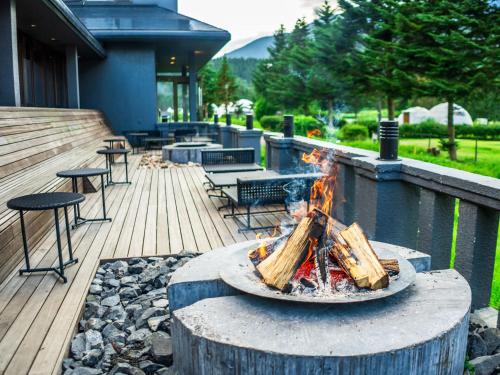 a fire pit on a deck with chairs and tables at Glamprook Iizuna in Iizuna