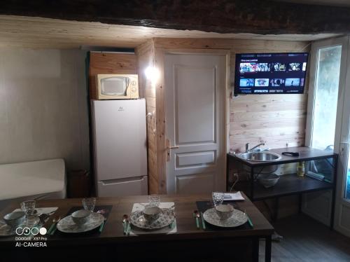 a small kitchen with a refrigerator and a table at Petit village authentique 2 in Mauléon-Barousse