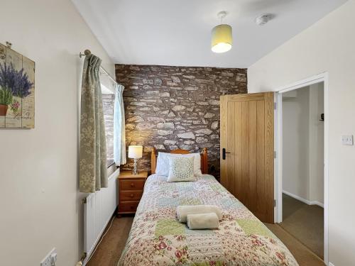 a bedroom with a bed and a stone wall at The Barn at Rainsbury House Upton in Upton