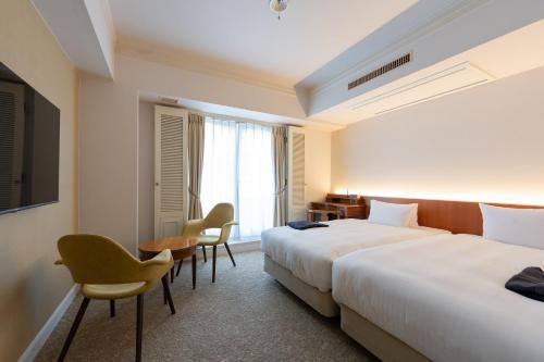 a hotel room with two beds and a table and chairs at Setre Glover's House Nagasaki in Nagasaki