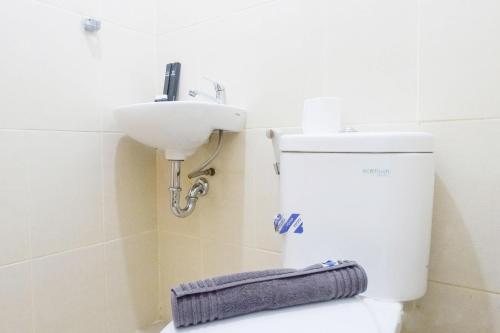 a bathroom with a sink and a toilet with a towel at Vibrant Modern Studio Room at Bale Hinggil Apartment By Travelio in Medokanayu