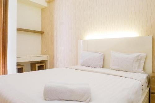 a white bed with white pillows in a room at Vibrant Modern Studio Room at Bale Hinggil Apartment By Travelio in Medokanayu