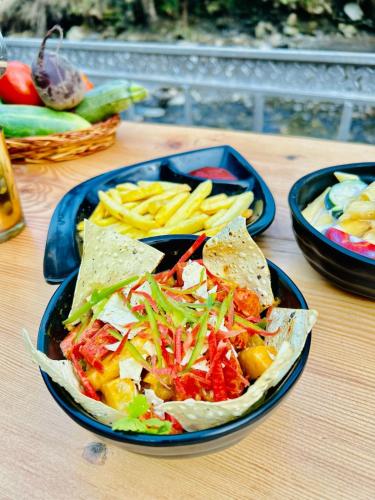 a plate of food with a salad and french fries at Alpine Stays Riverside in Jibhi