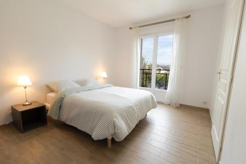une chambre blanche avec un lit et une fenêtre dans l'établissement Maison Cosy avec Jardin Paris Disney, à Bry-sur-Marne