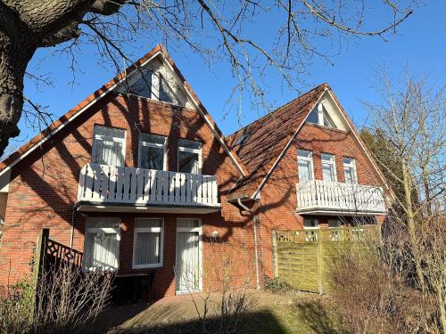 a red brick house with white balconies on it at Ferienwohnungen Hinrichs in Carolinensiel