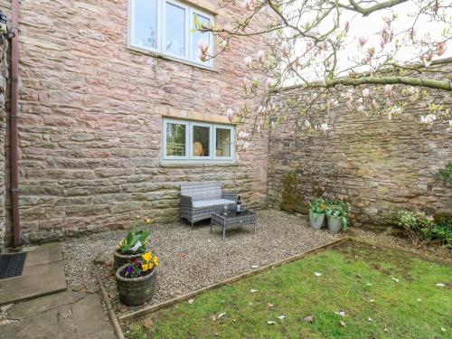 Un patio trasero con un banco y un edificio de ladrillos. en La'l Skaithe, en Kirkby Stephen