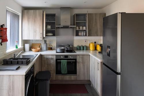 a kitchen with stainless steel appliances and wooden cabinets at Affordable House By Amara Apartments Short Term Rental Agency Coventry in Longford