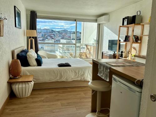 une chambre avec un lit et une grande fenêtre dans l'établissement Studio et piscine sur la grande plage, à Biarritz