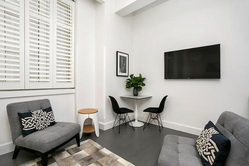 a living room with a couch and a table with chairs at CLDN4- Studio in Central Sydney CBD with Pool in Sydney