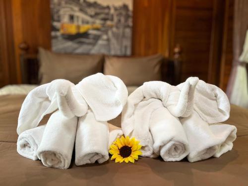 a pile of towels on a bed with a flower at Denchai City Resort เด่นชัยซิตี้ รีสอร์ท in Phrae